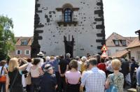 Entziffern der Tropfenbuchstaben: Gäste vor Skulptur und Radbrunnen